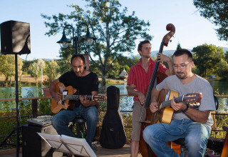 Muzikanten spelen gitaar en contrabas buiten op Camping Le Lac Bleu, Auvergne-Rhône-Alpes, Frankrijk.