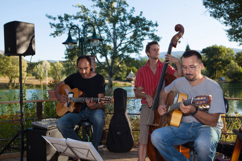 Musicisti suonano chitarra e contrabbasso all’aperto al Camping Le Lac Bleu, Auvergne-Rhône-Alpes, Francia.