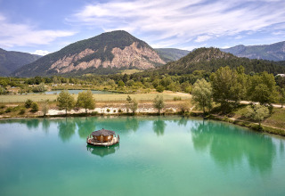 A scenic view of Camping Le Lac Bleu in Auvergne-Rhône-Alpes, France, with a lake and mountains.