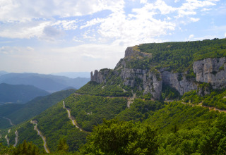 Vista panoramica di montagne verdi e strade tortuose vicino a Camping Le Lac Bleu in Alvernia-Rodano-Alpi, Francia.