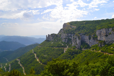 Vista panorámica de montañas verdes y caminos sinuosos cerca de Camping Le Lac Bleu en Auvergne-Rhône-Alpes, Francia.