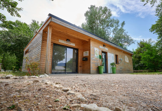 Modern houten gebouw bij Camping Le Lac Bleu, omgeven door bomen in Auvergne-Rhône-Alpes, Frankrijk.