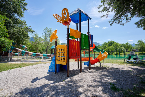 Parque infantil colorido con toboganes junto a un lago en Camping Le Lac Bleu, Auvergne-Rhône-Alpes, Francia.