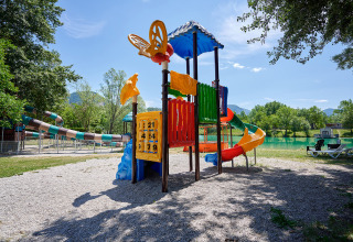 Colorful playground with slides near a lake at Camping Le Lac Bleu holiday park in Auvergne-Rhône-Alpes, France.