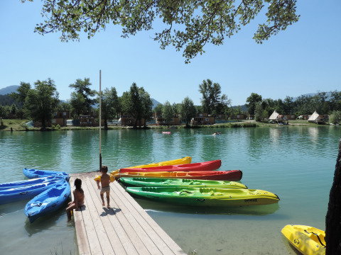 Bambini giocano su un pontile con kayak colorati sul lago al Camping Le Lac Bleu, Auvergne-Rhône-Alpes, Francia.