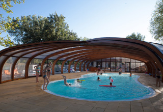 Børn og voksne nyder en overdækket swimmingpool på Camping Le Lac Bleu i Auvergne-Rhône-Alpes, Frankrig.
