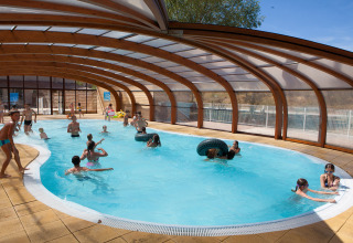 Children and adults play and swim in the covered pool at Camping Le Lac Bleu, Auvergne-Rhône-Alpes, France.