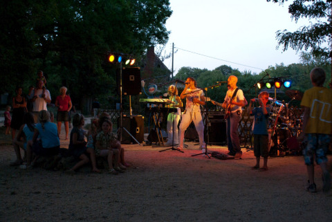 Concierto al aire libre en Camping Le Pech Charmant, Nouvelle-Aquitaine, Francia, con banda en vivo y público.