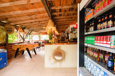 Vista interior de una sala rústica en Camping Le Pech Charmant con futbolín y refrigerador de bebidas.