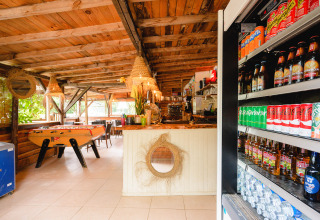 Interieur van een rustieke ruimte op Camping Le Pech Charmant met tafelvoetbal en drankfrigo.