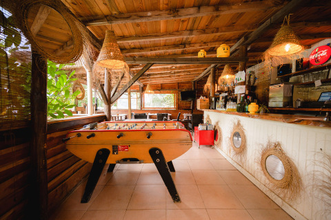 Interior de bar de madera con futbolín y decoración rústica en Camping Le Pech Charmant, Nouvelle-Aquitaine, Francia.