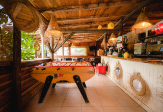 Gezellige houten bar met tafelvoetbal en rustieke accenten bij Camping Le Pech Charmant, Nouvelle-Aquitaine, Frankrijk.