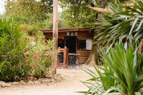 Bar al aire libre rodeado de vegetación en Camping Le Pech Charmant, parque vacacional en Nouvelle-Aquitaine, Francia.