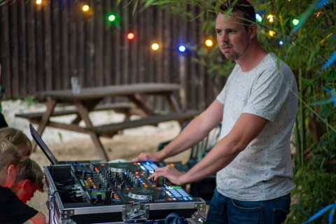 Un DJ actúa al aire libre con luces en Camping Le Pech Charmant, un parque vacacional en Nouvelle-Aquitaine, Francia.