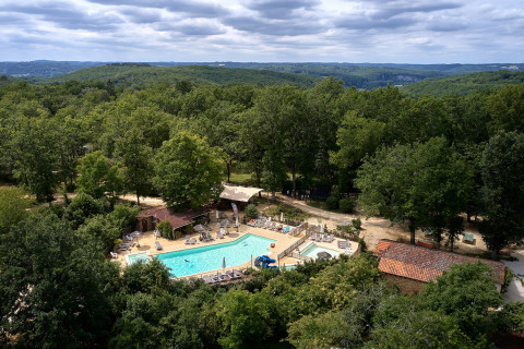 Vista aérea de Camping Le Pech Charmant con piscina rodeada de bosque en Nouvelle-Aquitaine, Francia.
