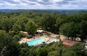 Luftfoto af Camping Le Pech Charmant med swimmingpool omgivet af skov, Nouvelle-Aquitaine, Frankrig.