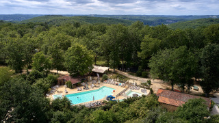 Vue aérienne du Camping Le Pech Charmant avec piscine entourée de forêt en Nouvelle-Aquitaine, France.