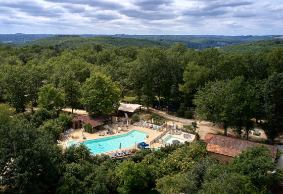 Luchtbeeld van Camping Le Pech Charmant met zwembad en bosrijke omgeving in Nouvelle-Aquitaine, Frankrijk.