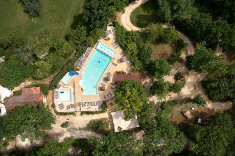 Vista aérea de una zona de piscina rodeada de árboles en Camping Le Pech Charmant, Nouvelle-Aquitaine.