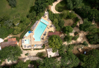 Luftfoto af swimmingpool-område omgivet af træer på Camping Le Pech Charmant i Nouvelle-Aquitaine.