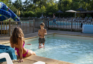 Vrouw en kind relaxen bij het kinderbad van Camping Le Pech Charmant, een vakantiedomein in Frankrijk.