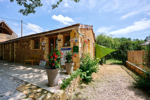 Camping Le Pech Charmant en Nouvelle-Aquitaine, Francia, edificio de piedra, día soleado, rodeado de naturaleza.