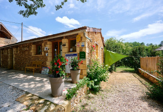 Camping Le Pech Charmant, vakantiepark in Nouvelle-Aquitaine, Frankrijk, stenen gebouw, planten en zon.