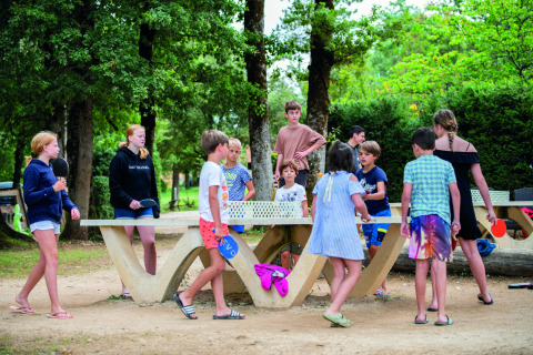 Niños jugando al tenis de mesa y reunidos al aire libre en el Camping Le Pech Charmant, Nueva Aquitania.
