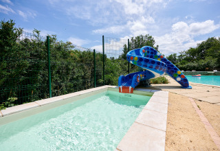 Een kleurrijke waterglijbaan eindigt in een kinderzwembad bij Camping Le Pech Charmant in Nouvelle-Aquitaine, Frankrijk.