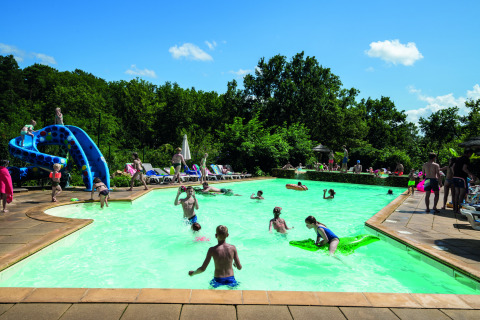 Familias y niños disfrutan de un día soleado en la piscina del Camping Le Pech Charmant en Nouvelle-Aquitaine.