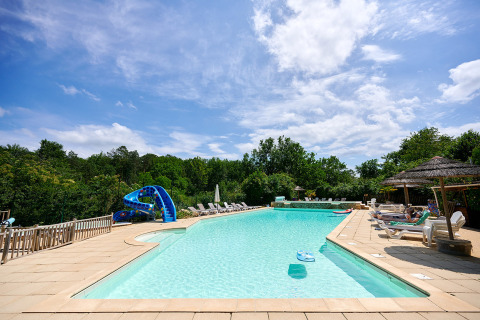 Piscina al aire libre con tumbonas, tobogán y sombrillas en Camping Le Pech Charmant en Nouvelle-Aquitaine.