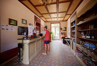 Reception del Camping Le Petit Trianon in Nouvelle-Aquitaine, Francia, con ospite al banco.