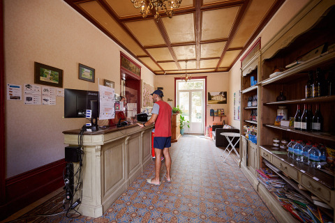 Receptionen på Camping Le Petit Trianon i Nouvelle-Aquitaine, Frankrig, med gæst ved skranken.