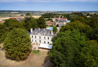 Luftfoto af Camping Le Petit Trianon, en feriepark omgivet af skov og marker i Nouvelle-Aquitaine, Frankrig.
