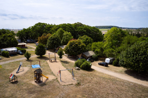 Vista aerea del Camping Le Petit Trianon in Nouvelle-Aquitaine con area giochi e roulotte.