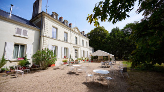 Gemütlicher Sitzbereich vor einem Herrenhaus im Ferienpark Camping Le Petit Trianon, Nouvelle-Aquitaine, Frankreich.
