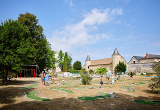 Familier nyder minigolf og legeplads i solen ved Camping Le Petit Trianon i Nouvelle-Aquitaine, Frankrig.
