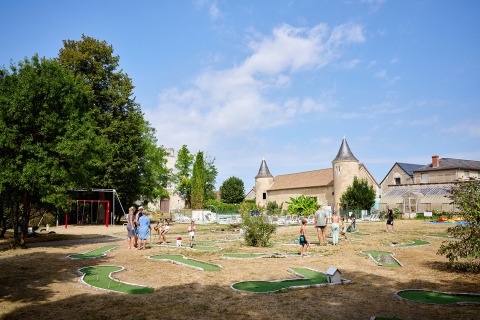 Famiglie si divertono con il minigolf e l’area giochi al Camping Le Petit Trianon in Nouvelle-Aquitaine, Francia.