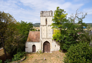 Et gammelt stenkapel skjult blandt træer ved Camping Le Petit Trianon i Nouvelle-Aquitaine, Frankrig.