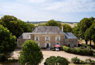 Luftfoto af Camping Le Petit Trianon feriepark i Nouvelle-Aquitaine, Frankrig, omgivet af grønne træer.
