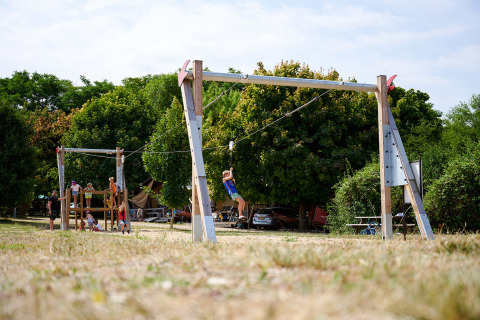 Kinder spielen auf einem Spielplatz mit Seilrutsche im Camping Le Petit Trianon in Nouvelle-Aquitaine, Frankreich.