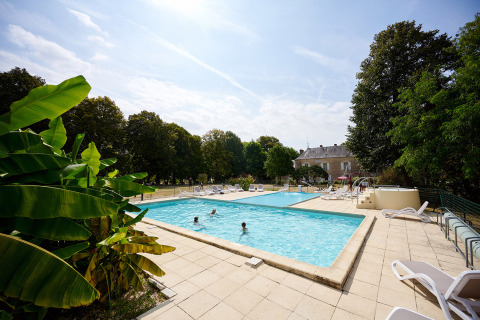 Piscina all'aperto con ospiti, lettini e alberi al Camping Le Petit Trianon in Nouvelle-Aquitaine, Francia.