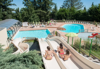 Børn nyder vandrutsjebaner ved swimmingpoolen i Camping Le Sequoia, en feriepark i Nouvelle-Aquitaine, Frankrig.