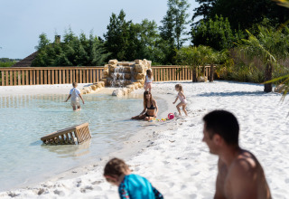 Families enjoying the sandy poolside and sunshine at Camping Le Sequoia in Nouvelle-Aquitaine, France.