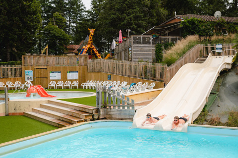 Two people slide down water slides at Camping Le Sequoia holiday park in Nouvelle-Aquitaine, France.
