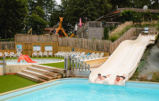 Two people slide down water slides at Camping Le Sequoia holiday park in Nouvelle-Aquitaine, France.