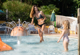 Een vrouw en een kind spelen in het kinderzwembad bij Camping Le Sequoia in Nouvelle-Aquitaine, Frankrijk.