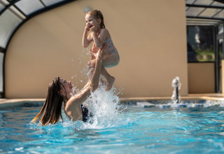 Moeder en dochter spelen in het overdekte zwembad van Camping Le Sequoia vakantiepark in Nouvelle-Aquitaine, Frankrijk.