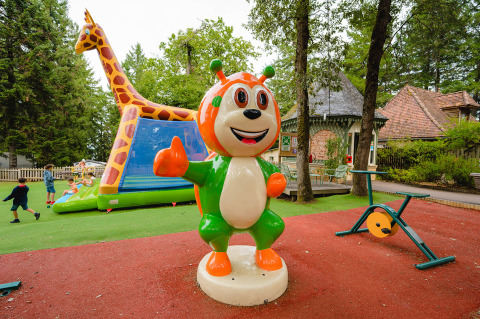 Playground at Camping Le Sequoia in Nouvelle-Aquitaine, France, with colorful mascot statue and children playing.