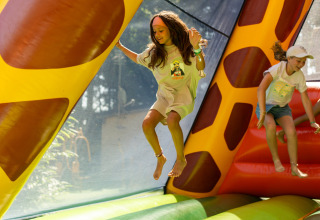 Kinderen springen en spelen in een springkasteel op Camping Le Sequoia in Nouvelle-Aquitaine, Frankrijk.